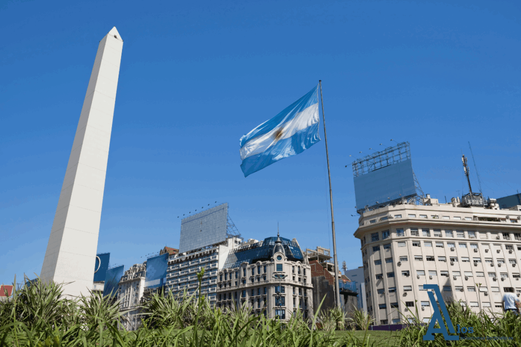 Vista panorámica de la Plaza con el Obelisco de Buenos Aires y una bandera argentina ondeando al viento
