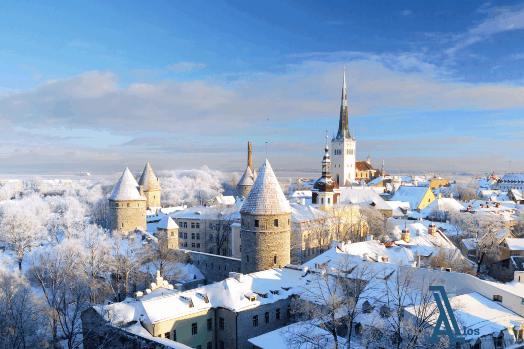 Vista invernal del castillo de Tallin cubierto de nieve, con torres medievales y tejados nevados del casco antiguo.