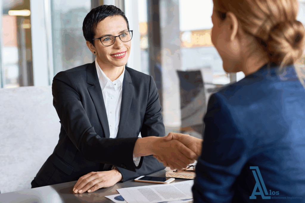 Mujeres profesionales estrechando la mano tras una reunión exitosa, representando el uso del inglés para negociaciones y reuniones empresariales en un entorno corporativo.